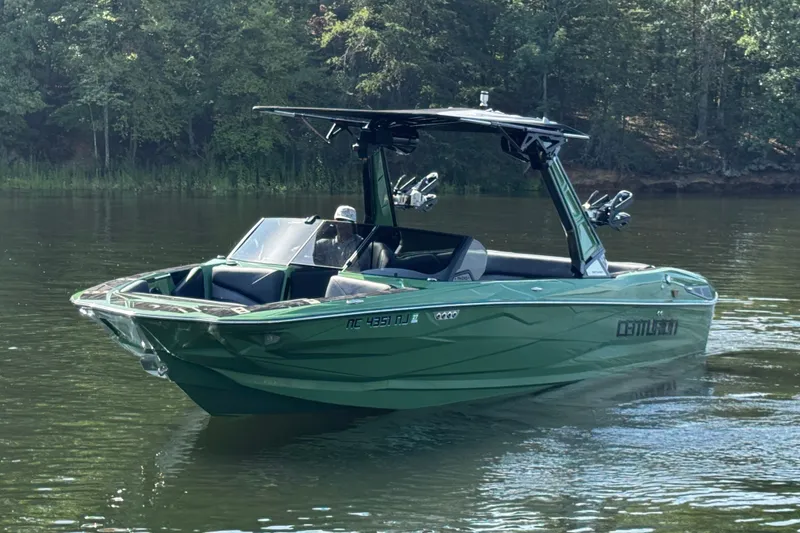 Slide: The Image of 2026 Centurion Nv243 boat on calm water, surrounded by lush greenery. - 14