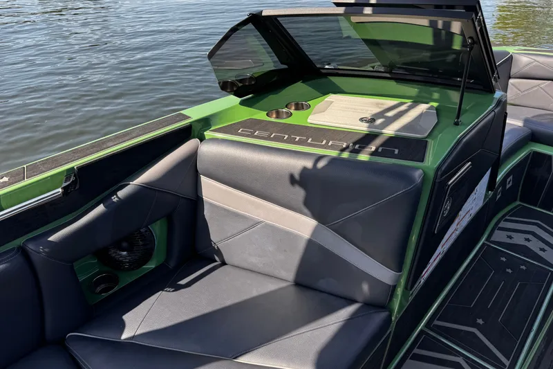 Slide: The Image of 2026 Centurion Nv243 boat interior with green and gray seating, on calm water. - 20