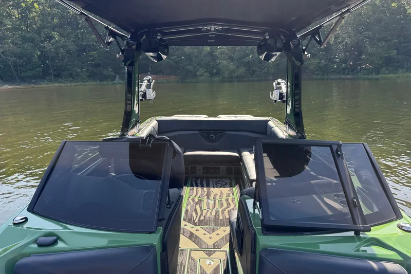 Slide: The Image of 2026 Centurion Nv243 boat interior with open windshield, on a calm lake. - 18