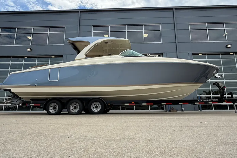 The Image of 2027 Chris-Craft Launch 35 GT boat on trailer, parked outside modern building. - 1