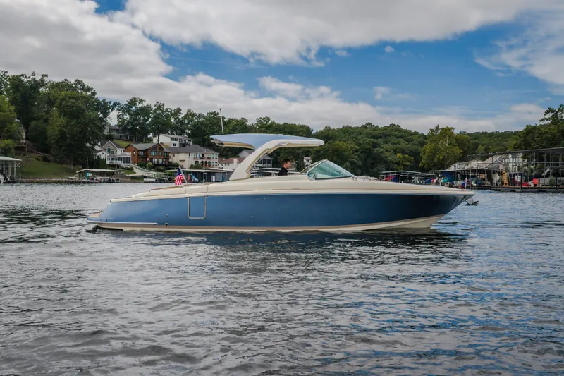 The Image of 2027 Chris-Craft Launch 35 GT boat on a scenic lake with houses in the background. - 2