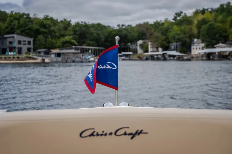 Slide: The Image of 2027 Chris-Craft Launch 35 GT boat on a lake with flag and shoreline view. - 74
