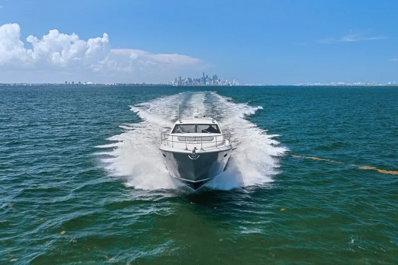 Slide: The Image of 2005 Uniesse 54 Sport yacht cruising on open water with city skyline backdrop. - 2