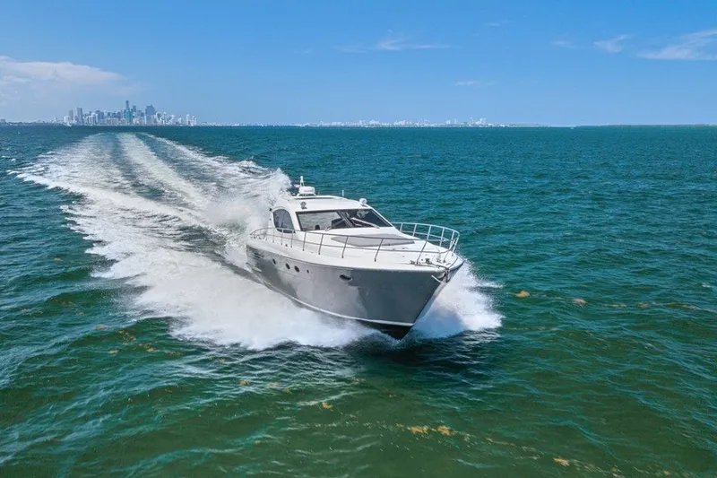Slide: The Image of 2005 Uniesse 54 Sport yacht cruising on open water with city skyline backdrop. - 3