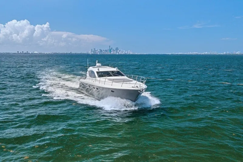 Slide: The Image of 2005 Uniesse 54 Sport yacht cruising on open water with city skyline in background. - 6