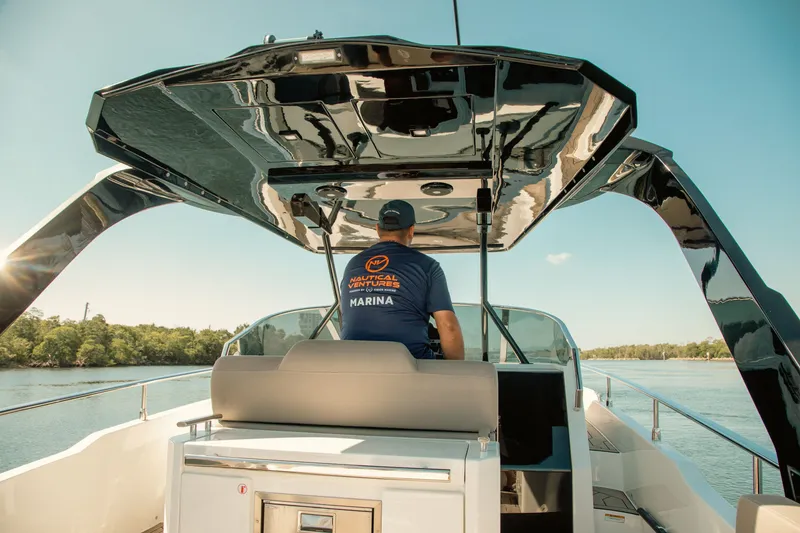 Slide: The Image of Man steering 2024 FIM 34 Regina boat on a sunny day, surrounded by water and trees. - 14