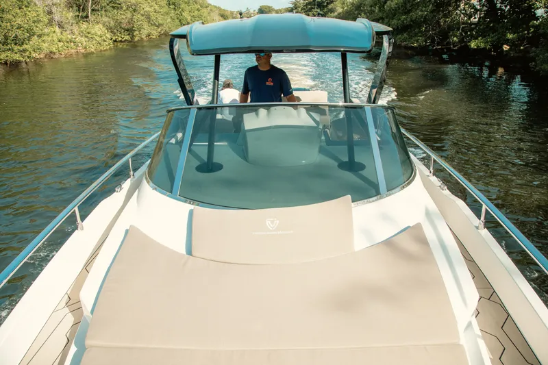 Slide: The Image of 2024 FIM 34 Regina boat cruising on a scenic river with lush greenery. - 29