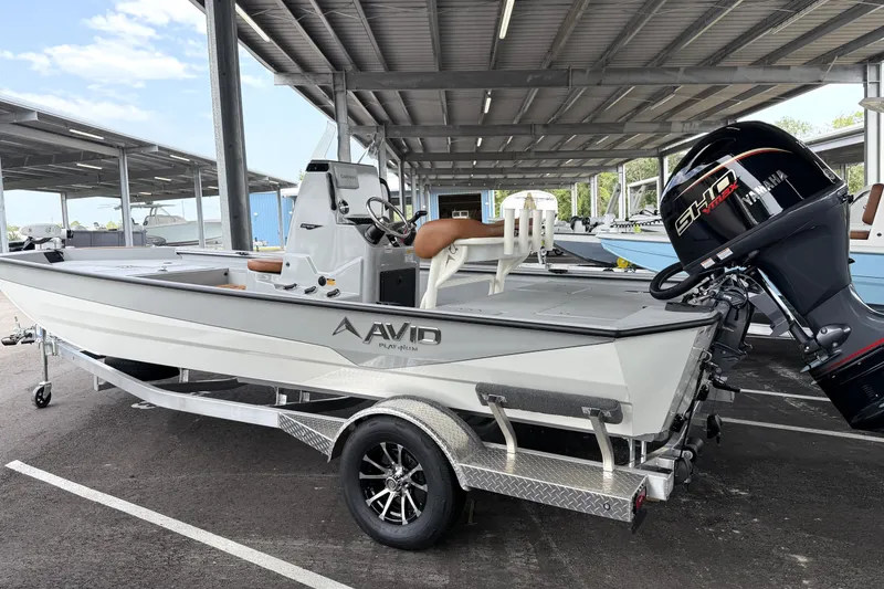 The Image of 2027 Avid 207 Recon boat on trailer, under covered parking, with powerful outboard motor. - 0