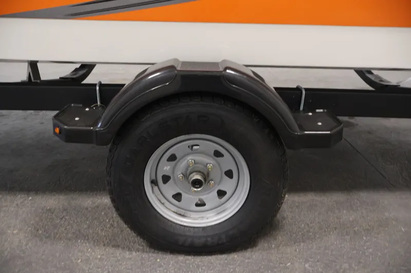 Slide: The Image of Trailer wheel of 2019 Bayliner Element 180 XL boat, featuring black fender and orange hull. - 39