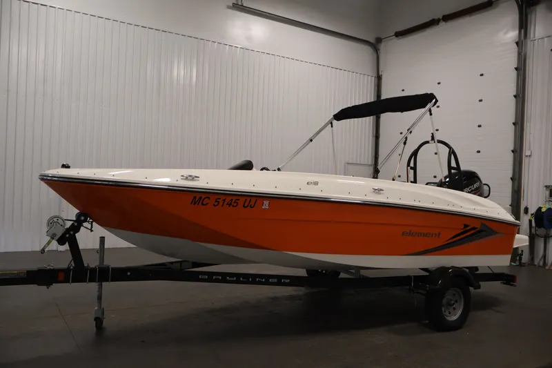 Slide: The Image of 2019 Bayliner Element 180 XL boat with orange hull on trailer in indoor setting. - 8