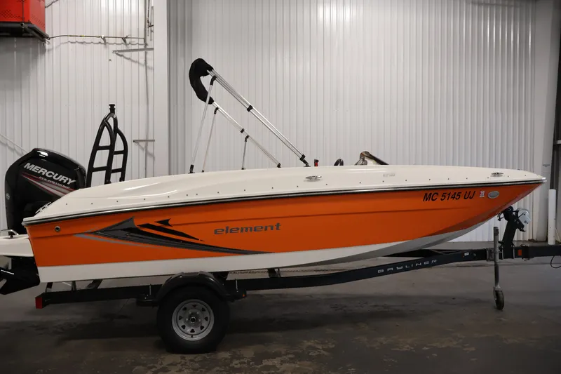 Slide: The Image of 2019 Bayliner Element 180 XL boat with orange hull on trailer in indoor storage. - 4
