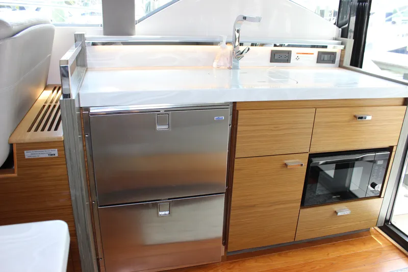 Slide: The Image of 2019 Tiara Yachts C39 Coupe kitchen with stainless steel appliances and wooden cabinetry. - 65
