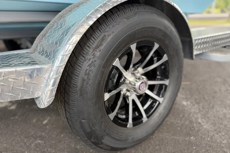 Slide: The Image of Close-up of a 2027 Avid 19 FSX trailer wheel with black alloy rim and diamond plate fender. - 13