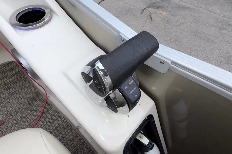 Slide: The Image of Throttle control on a 2015 Bennington 2550 RSR boat, featuring a cup holder and carpeted flooring. - 44