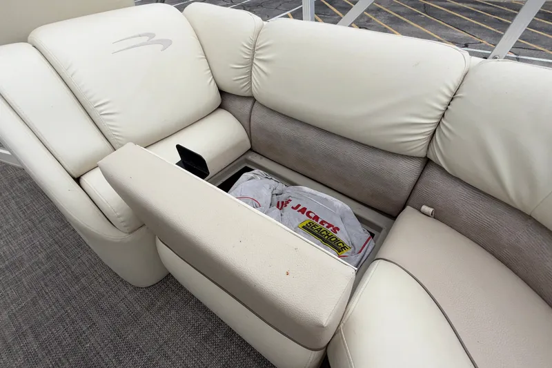 Slide: The Image of 2015 Bennington 2550 RSR boat seat with storage compartment open, revealing life jackets. - 32