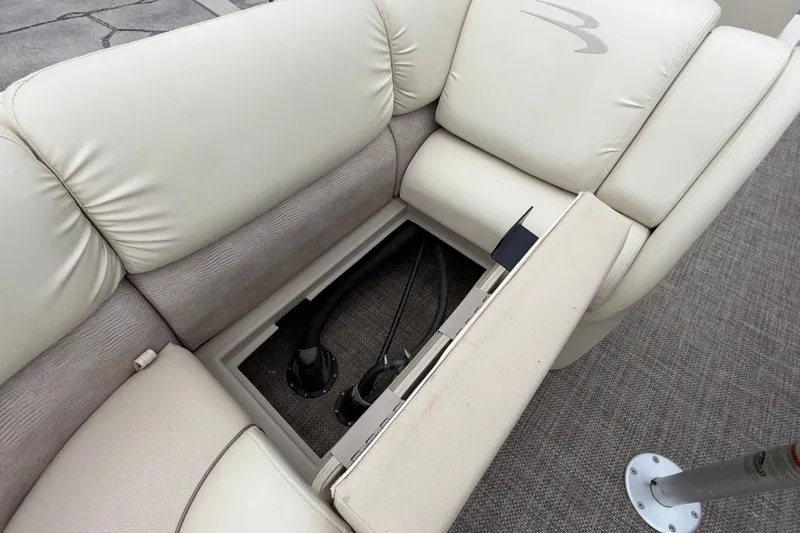 Slide: The Image of 2015 Bennington 2550 RSR boat seat storage compartment with open lid, revealing interior components. - 29