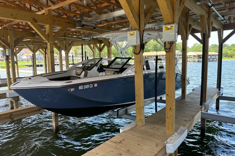 The Image of 2023 Yamaha Boats 275SDX docked in a wooden boathouse over water. - 0