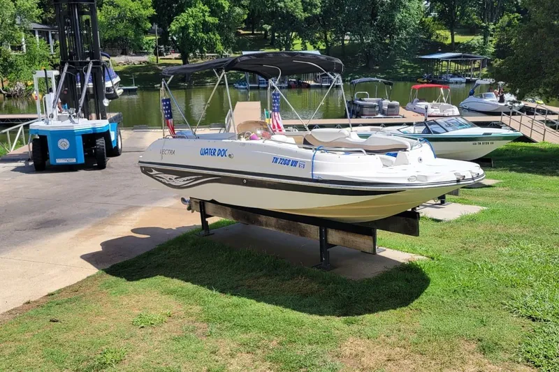 Slide: The Image of 2005 Vectra S-200 boat on lift by lakeside dock, surrounded by trees and other boats. - 7