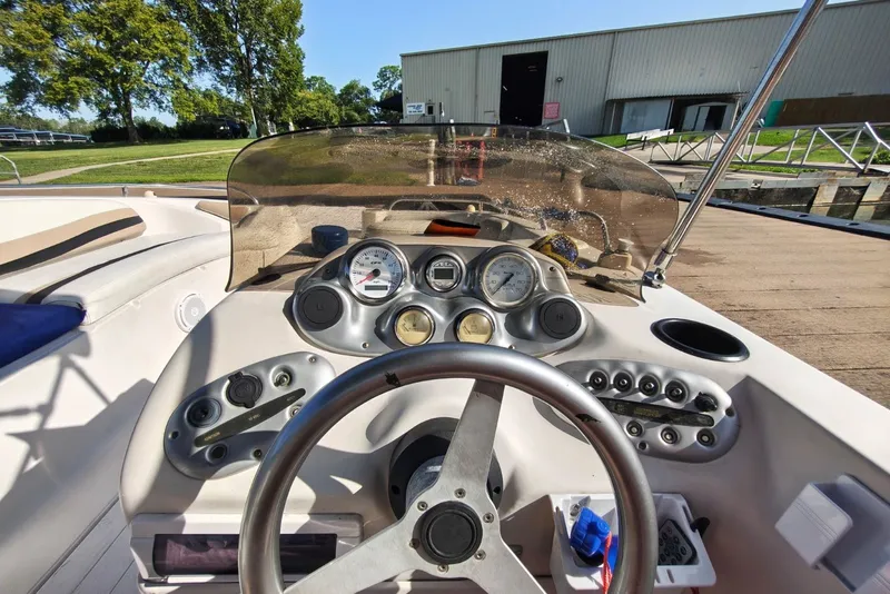 Slide: The Image of Steering console of a 2005 Vectra S-200 boat, docked near a grassy area. - 11