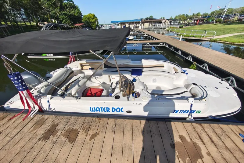 Slide: The Image of 2005 Vectra S-200 boat named "Water Doc" docked with canopy and American flags. - 5