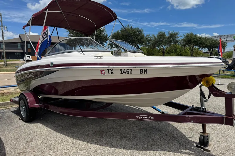 Slide: The Image of 2009 Tahoe Q4 SS boat on trailer, maroon and white, parked outdoors under blue sky. - 6