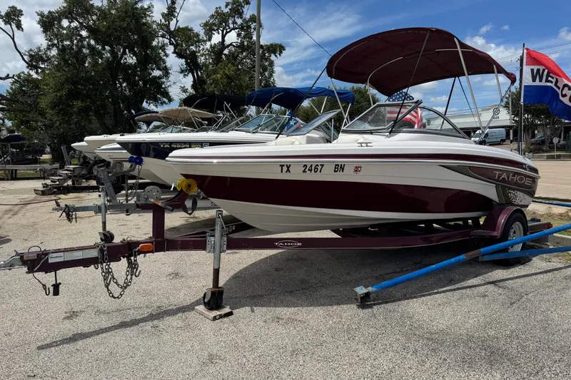 Slide: The Image of 2009 Tahoe Q4 SS boat on trailer, parked outdoors with welcome flag in background. - 2