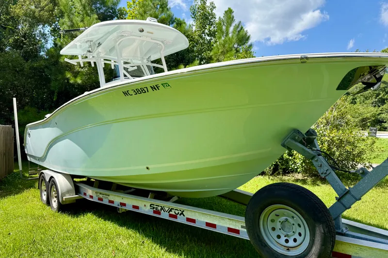 Slide: The Image of 2017 Sea Fox 288 Commander boat on trailer, parked on grass with trees in background. - 7