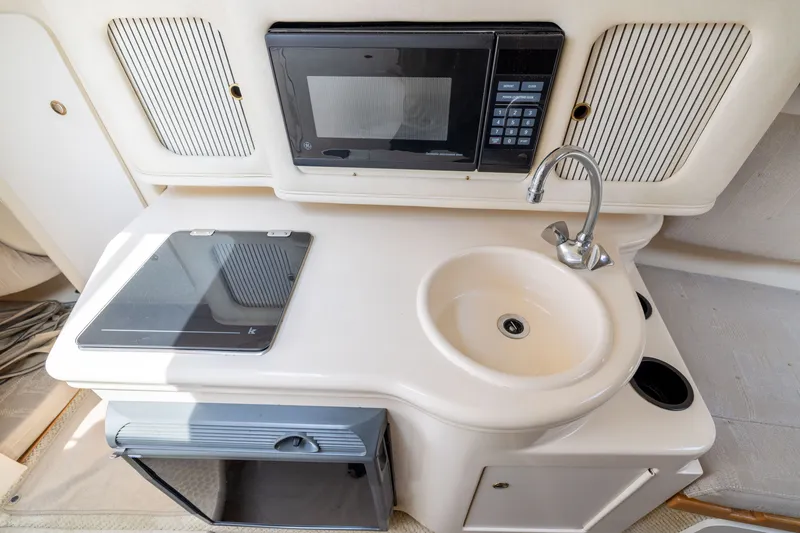 Slide: The Image of Compact kitchen area in a 2002 Sea Ray Sundancer 260 boat with sink, stove, and microwave. - 18