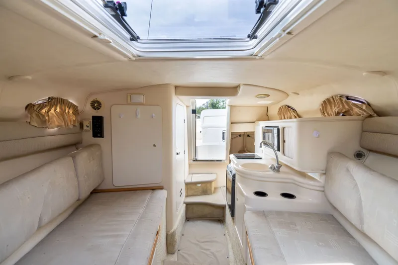 Slide: The Image of Interior of 2002 Sea Ray Sundancer 260 boat, featuring cozy seating and compact kitchenette. - 17