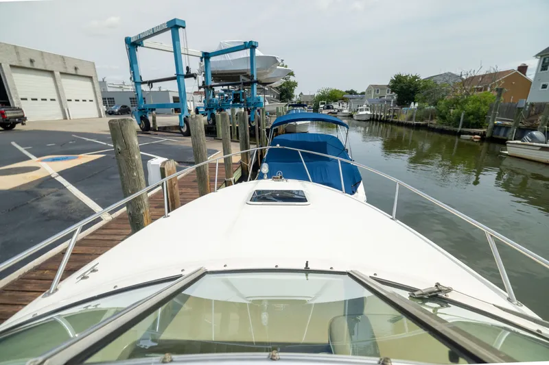 Slide: The Image of 2002 Sea Ray Sundancer 260 docked at a marina with boat lift and calm water. - 14