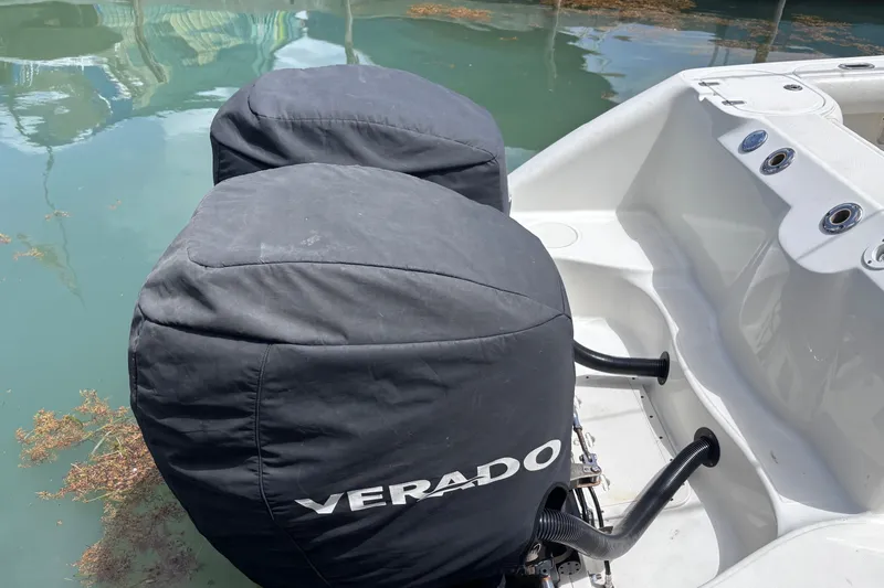 Slide: The Image of Boston Whaler Outrage 270 boat with covered Verado engines, docked on calm water. - 15