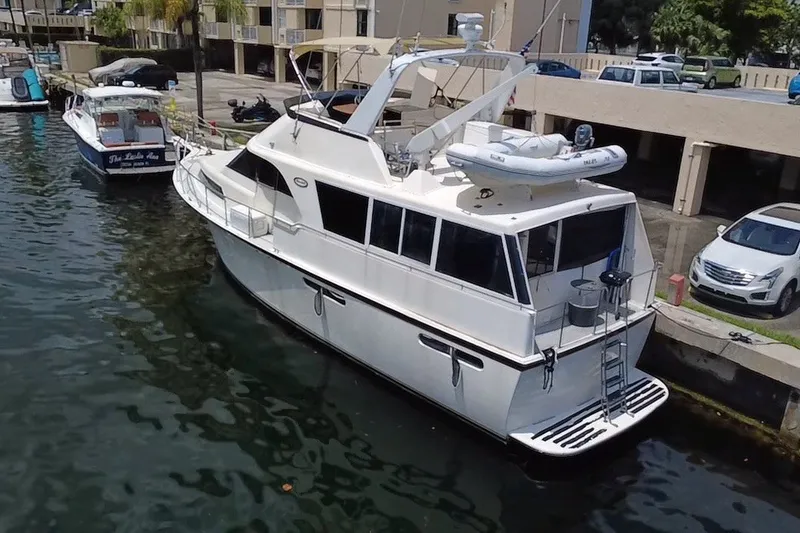 Slide: The Image of 1989 Ocean Yachts 48 Motor Yacht docked at marina, featuring spacious deck and dinghy. - 123