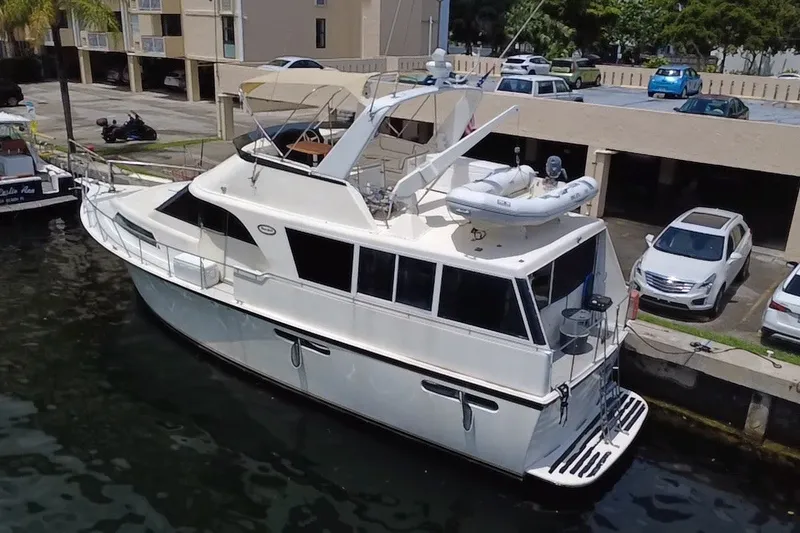 Slide: The Image of 1989 Ocean Yachts 48 Motor Yacht docked at marina, featuring upper deck and tender. - 124