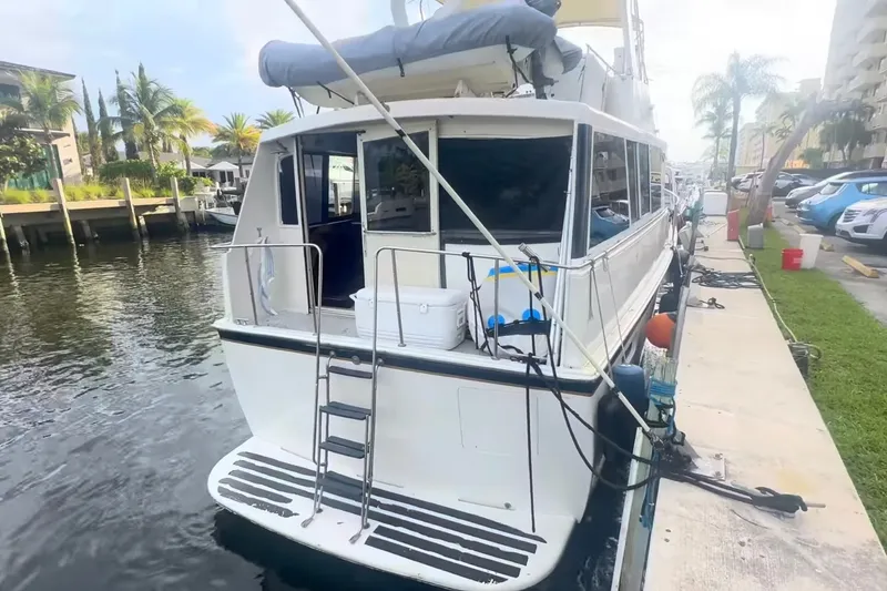 The Image of 1989 Ocean Yachts 48 Motor Yacht docked by a waterfront with palm trees. - 0