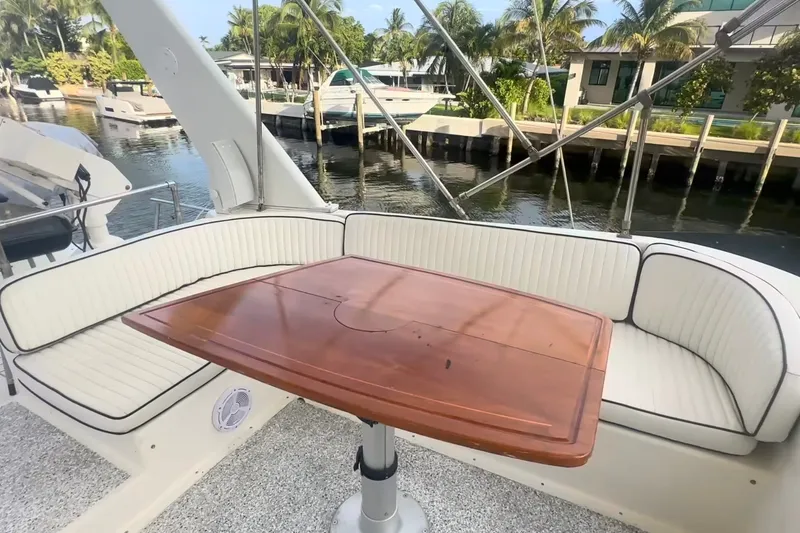 Slide: The Image of 1989 Ocean Yachts 48 Motor Yacht with elegant seating and wooden table, docked by palm trees. - 40
