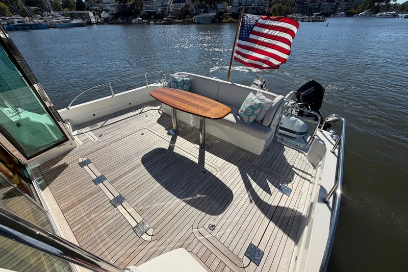 Slide: The Image of 2020 Sabre 58 Salon Express yacht deck with seating, table, and American flag. - 37