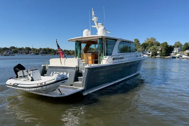 Slide: The Image of 2020 Sabre 58 Salon Express yacht on calm water with a small boat attached. - 45
