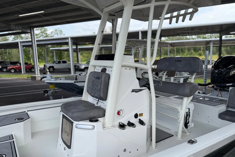 Slide: The Image of 2027 Avid 23 Mag boat interior with seating and control panel in a covered parking area. - 5