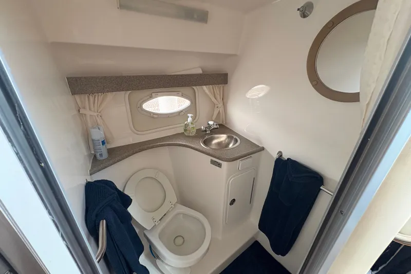 Slide: The Image of 2008 Rinker 320 Express Cruiser bathroom with sink, toilet, and porthole window. - 21