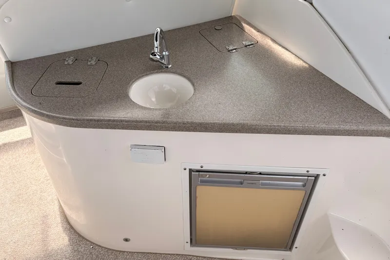 Slide: The Image of 2008 Rinker 320 Express Cruiser kitchenette with sink, faucet, and storage compartments. - 11