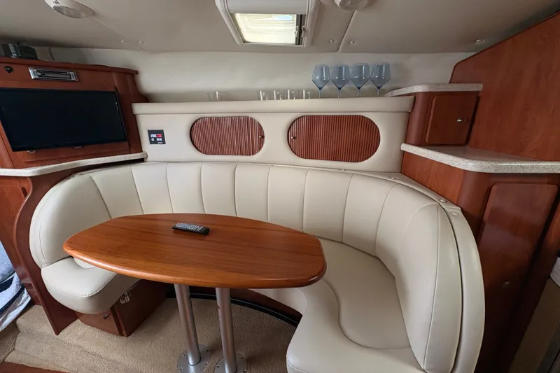 Slide: The Image of 2008 Rinker 320 Express Cruiser interior with curved seating and wooden table. - 20