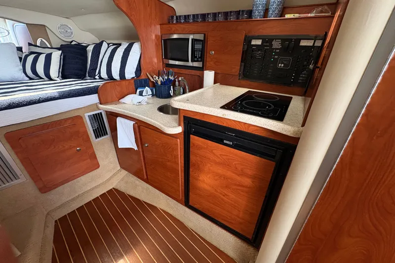 Slide: The Image of 2008 Rinker 320 Express Cruiser interior with kitchenette and cozy sleeping area. - 22