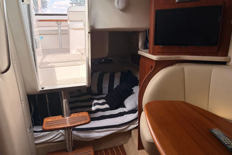 Slide: The Image of Interior of 2008 Rinker 320 Express Cruiser with cozy seating and striped bedding. - 15