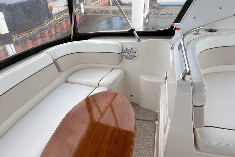 Slide: The Image of 2008 Rinker 320 Express Cruiser interior with white seating and wooden table. - 10