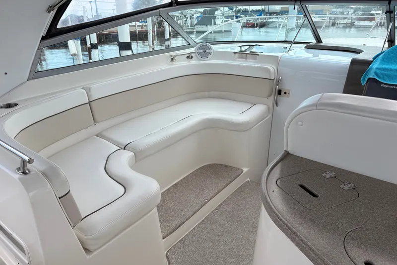 Slide: The Image of Interior of a 2008 Rinker 320 Express Cruiser with white seating and marina view. - 9