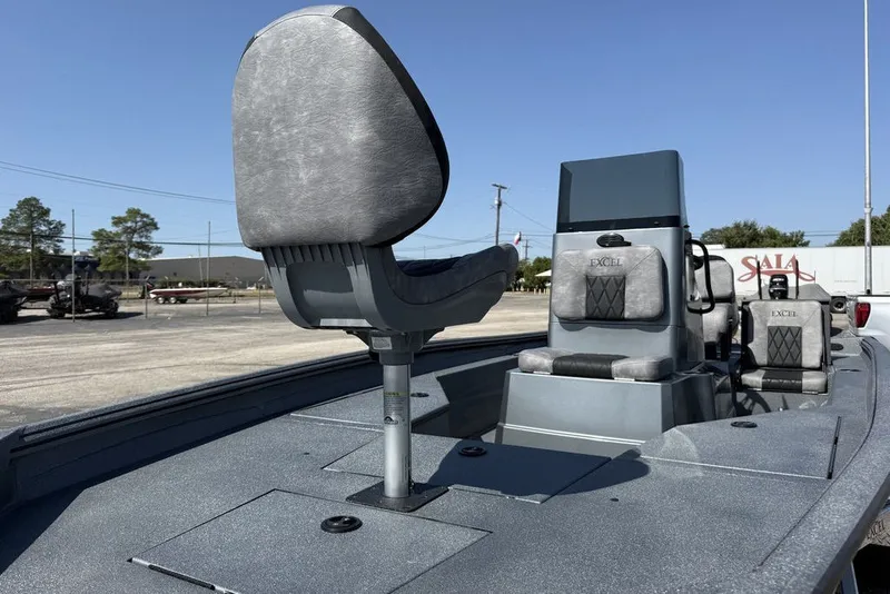 Slide: The Image of 2027 Excel 203 Bay Pro Elite boat interior with seating and console, parked outdoors. - 20