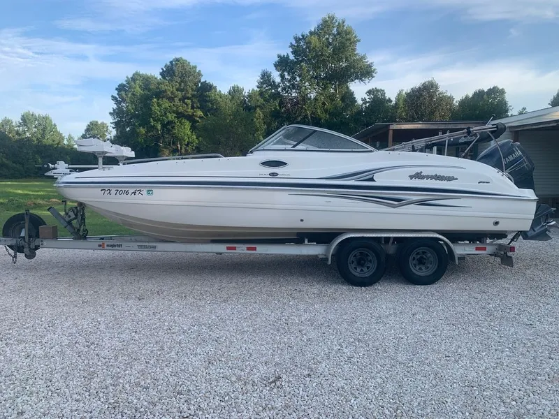 The Image of A 2006 Hurricane SunDeck 230 OB on a trailer in a gravel area. - 0