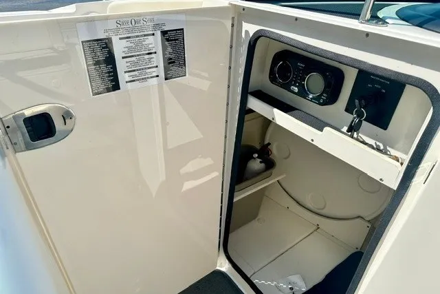Slide: The Image of 2013 Sea Ray 240 Sundeck interior storage compartment with control panel and safety equipment. - 21