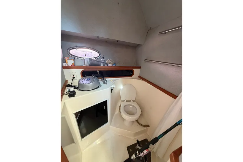 Slide: The Image of Bathroom interior of 1990 Tiara Yachts 3300 Open, featuring toilet and storage space. - 14