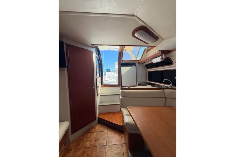 Slide: The Image of Interior of 1990 Tiara Yachts 3300 Open, featuring a cozy dining area and kitchenette. - 13